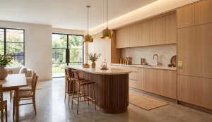 מטבח מודרני עם אי מעוגל מעץ אלון, גופי תאורת פליז ונוף לגינה
